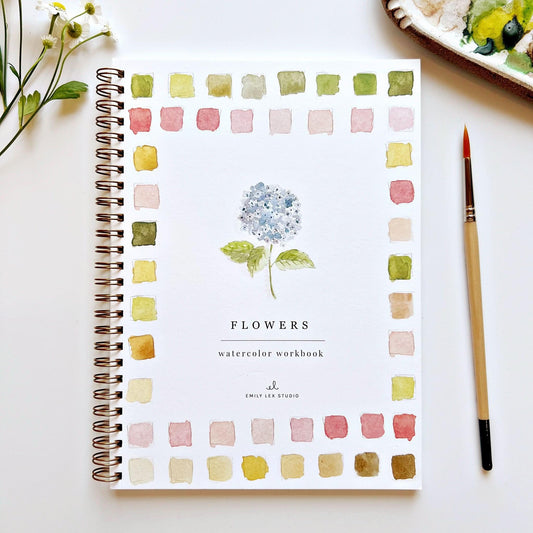 Watercolor workbook titled 'Watercolor Workbook Flowers' by Emily Lex Studio on a white surface with a brush and flowers.
